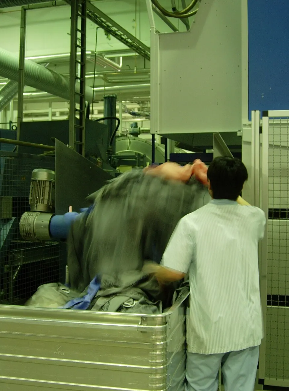 Déchargement du linge dans un bac roulant en sortie de séchage industriel